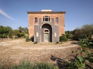 um velho edifício de tijolos com uma porta num campo em Zahara em Carlentini