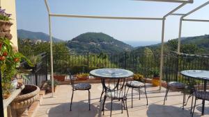 eine Terrasse mit Tischen, Stühlen und Bergen im Hintergrund in der Unterkunft B&B la taverna degli Angeli in Vezzi Portio