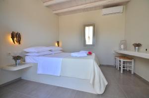 a white bedroom with a bed with white sheets and pillows at Portes Houses in Koufonisia