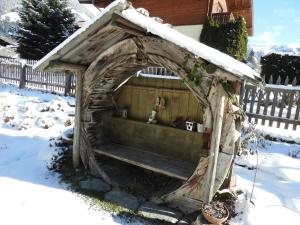 a dog house with a bench in the snow at Landhaus Rasser in Rauris