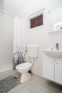 a white bathroom with a toilet and a sink at Apartments Dara in Rogoznica +60 photos