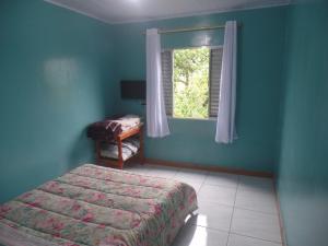 a blue bedroom with a bed and a window at pousada ferreira's in Paranapiacaba