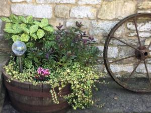 una rueda de carruaje de madera con flores en un jardín en The Horse Barn en Corsham