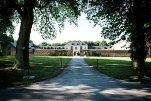 uma estrada que leva a um grande edifício com árvores em Domaine De Barive em Sainte-Preuve