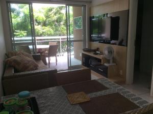 a living room with a couch and a tv and a balcony at Condomínio Palm Beach in Aquiraz