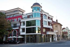 un gran edificio en una calle con mesas y sombrillas en Hotel Diamond en Kazanlŭk