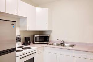 eine weiße Küche mit einer Spüle und einer Mikrowelle in der Unterkunft Sage Inn Merritt BC in Merritt