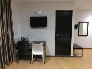 a dining room with a table and a television on the wall at Padungan Hotel in Kuching
