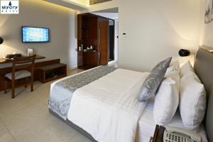 a bedroom with a bed and a desk and a television at Sky City Hotel Dhaka in Dhaka