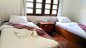 een kamer met twee bedden, een tafel en een raam bij Syvongsack Guesthouse in Pakbeng +13 foto's