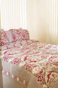 a bed with a red and white quilt on it at Casa De Pedro in Mangilao