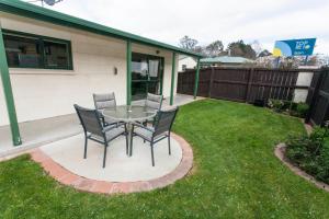 a patio with a table and chairs in the grass at Oamaru TOP 10 Holiday Park in Oamaru