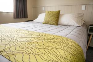 a large bed with a yellow and white blanket at Oamaru TOP 10 Holiday Park in Oamaru