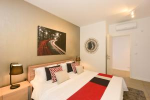 a bedroom with a white bed with red and black pillows at Luxury Apartment - Azuri Village - Roches Noires in Roches Noires