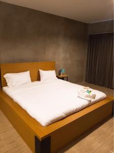 a bedroom with a large bed with white sheets at The Day Home Hotel in Pak Chong