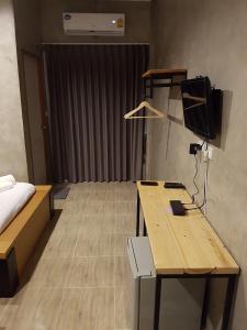a room with a desk and a bed and a television at The Day Home Hotel in Pak Chong