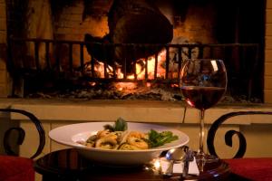 a plate of food and a glass of wine on a table with a fireplace at Erzurumlu Hotel in Kilyos