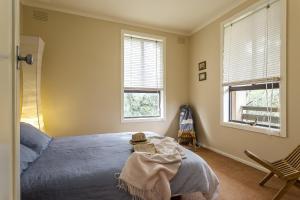 a bedroom with a bed and two windows at Salty Dog by the Sea - Pet Friendly in Rye