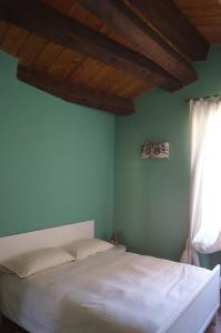 a bedroom with a white bed with a green wall at In the heart of Verona in Verona