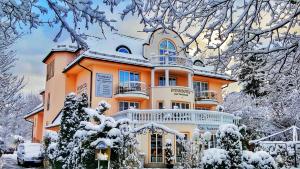 ein großes orangenes Gebäude mit Schnee drauf in der Unterkunft Parkhotel Bad Faulenbach in Füssen