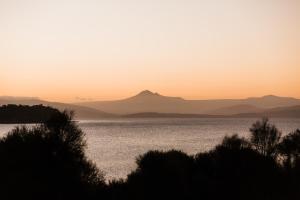 a sunset over the water with mountains in the background at Manfield Seaside Bruny Island in Alonnah