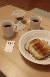 einen Tisch mit zwei Tassen Kaffee und einem Teller Toast in der Unterkunft Byulbam Guesthouse in Gwangju