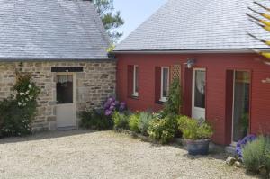 a red cottage with flowers in front of it at Location de La Ferme De Kerraoul in Combrit