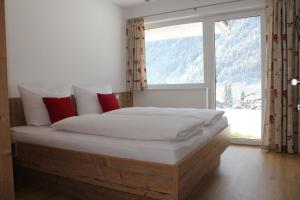 Bett in einem Zimmer mit einem großen Fenster in der Unterkunft Appart Stefanie in Sankt Gallenkirch