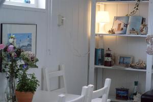 エグモント・アーン・ゼーにあるEgmondaanzeevakantiehuisjeのダイニングルーム(白い椅子、花瓶付きのテーブル付)