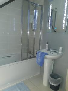 a white bathroom with a sink and a shower at Sams cottage in Corderry