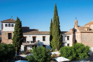 un grand bâtiment avec des arbres devant lui dans l'établissement Hotel Cortijo del Marqués, à Albolote