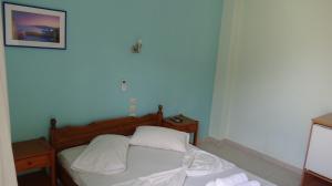 - une chambre avec un lit doté de draps et d'oreillers blancs dans l'établissement Poros House Hotel, à Poros