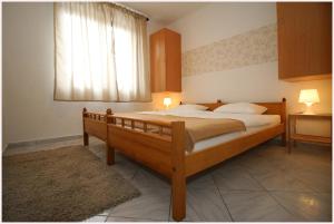 Schlafzimmer mit einem großen Holzbett und einem Fenster in der Unterkunft Apartments L&M in Rogoznica