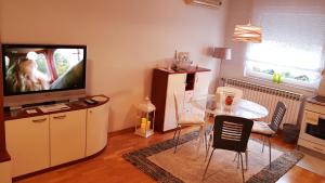 a living room with a television and a table with chairs at Apartment Dominik in Osijek