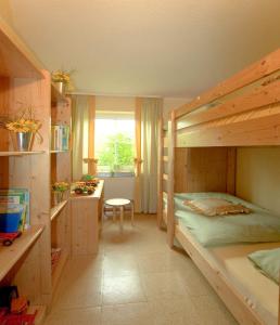 バート・ベルネック・イム・フィヒテルゲビルゲにあるFerienhof Hübnerの二段ベッド1組、デスクが備わる小さな客室です。