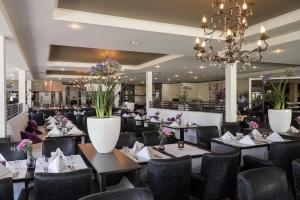a restaurant with tables and chairs and a chandelier at Van der Valk Hotel Goes in Goes