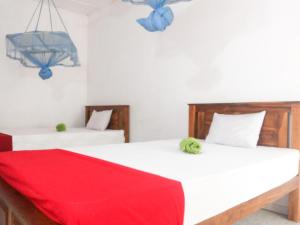 two beds in a room with a red blanket on them at Jayaru Guest House in Polonnaruwa +65 photos