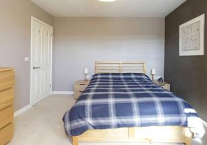 a bedroom with a bed with a blue and white plaid blanket at D&E Homestay in Wallingford