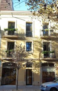 un edificio con balconi e un albero di fronte ad esso di Ten To Go Hostel a Barcellona