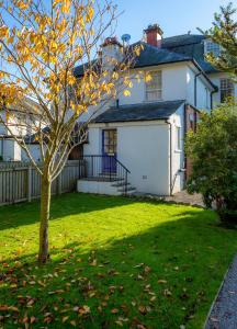 a white house with a tree in the yard at The Garden Apartment in Keswick