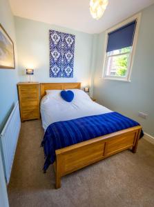 a bedroom with a bed with blue sheets and a window at The Garden Apartment in Keswick