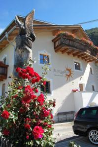 a christmas tree in front of a building with red roses at Morigglhof in Malles Venosta