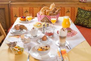 a breakfast table with food and drinks and a basket of food at Hotel Binggl in Obertauern