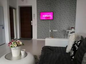 a living room with a tv and flowers on a table at White Luxury Apartment in Sibiu