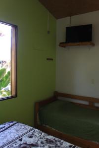 um quarto verde com uma cama e uma janela em Pousada O Canto das Sereias em Trindade