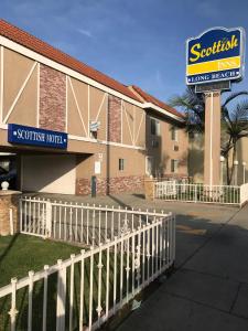 una señal para una posada en el sur frente a un edificio en Scottish Inns en Long Beach