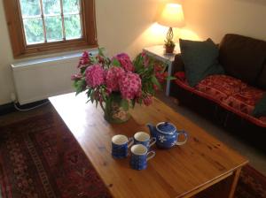 a living room with a coffee table with a vase of flowers at Maescelyn in Aberystwyth