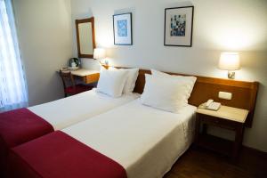 a hotel room with two beds and two lamps at Hotel Solaris in Setúbal