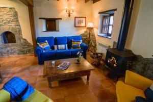a living room with a blue couch and a wood stove at Cai Llope in Oviñana