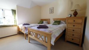 a bedroom with two beds and a dresser at Frome Cottages in Evershot